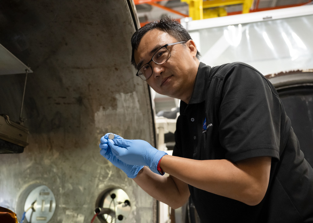 Yi Lin sostiene una batería de botón probada por el equipo SPEARS de NASA Langley.