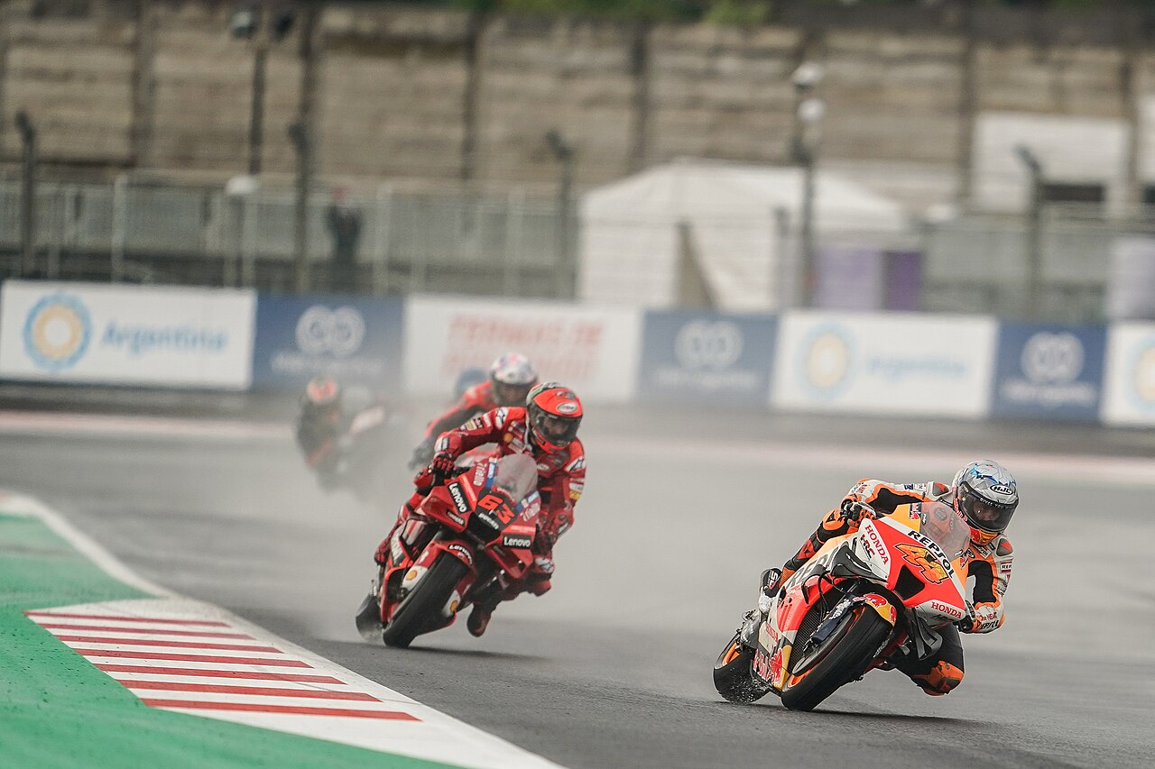 Varias motocicletas compiten sobre el asfalto mojado de Mandalika en 2022.